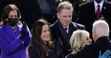 Hunter Biden in a suit looks on as Jill Biden embraces Joe Biden and Kamala Harris in a blue pantsuit claps enthusiastically