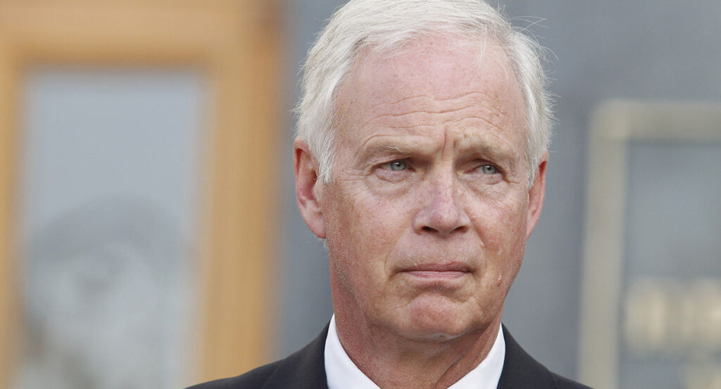Elderly white man scowls in a suit and white hair