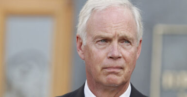 Elderly white man scowls in a suit and white hair