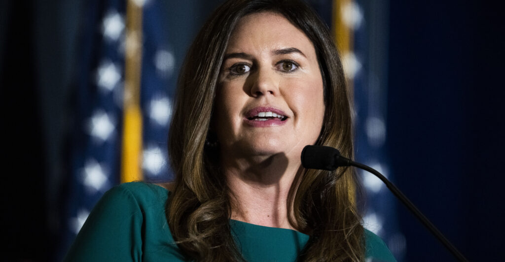 Sarah Huckabee Sanders in front of American flags