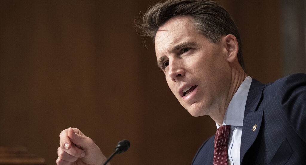 Josh Hawley gestures in a suit