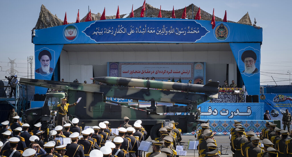 A military vehicle carrying an Iranian surface-to-surface missile past portraits of Supreme Leader Ayatollah Ali Khamenei