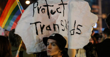 Activist marches with a sign reading "protect trans kids"