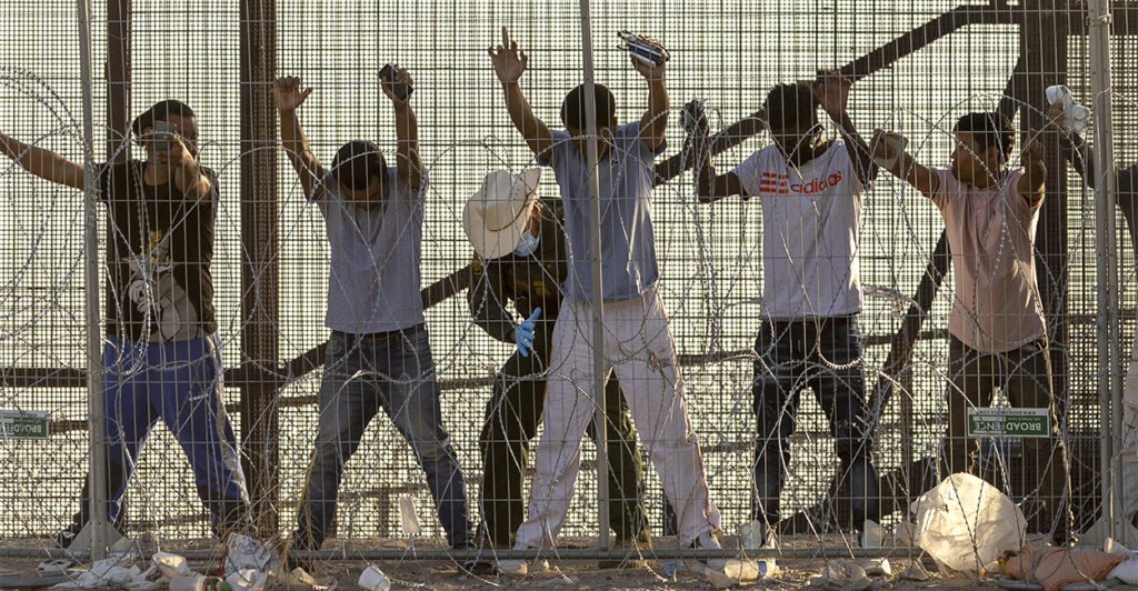 U.S. Border Patrol agent body searches illegal aliens at the U.S.-Mexico border