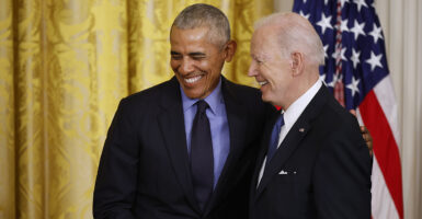 Barack Obama and Joe Biden smiling together in suits