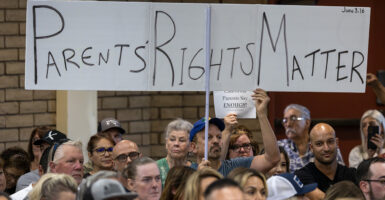 Man holds sign reading "Parents' Rights Matter" at school board meeting