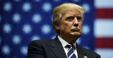 Donald Trump wearing a suit in front of an American flag