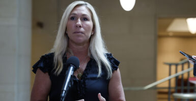 Marjorie Taylor Greene in a dress speaks in front of a microphone