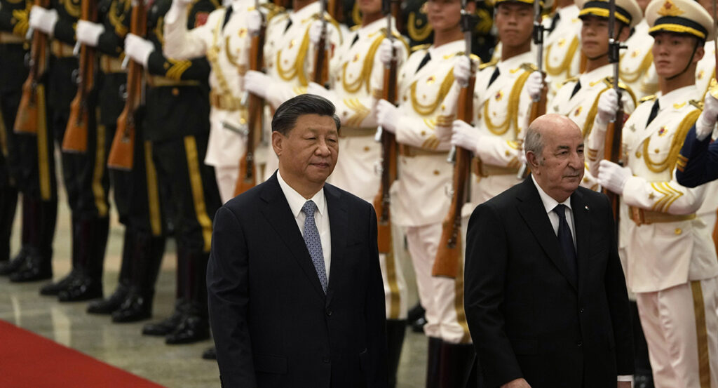 Chinese President Xi Jinping, wearing a suit, walks in front of Chinese soldiers