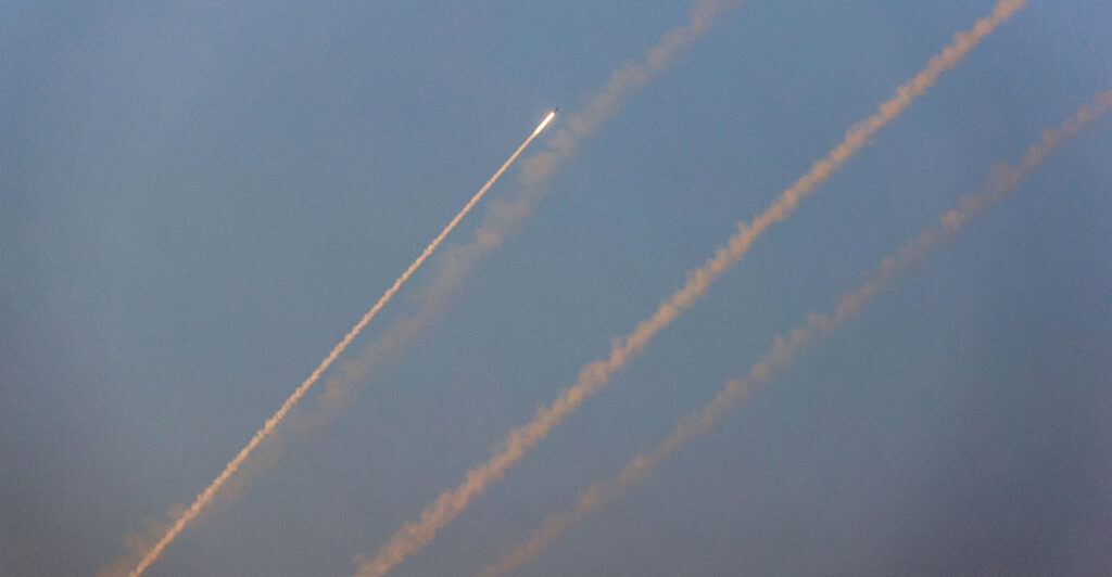 Rockets fly towards Israel against a blue sky.