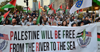 Pro-Palestine protesters march behind a banner reading "Palestine will be free from the river to the sea."