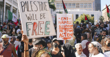 Protesters hold Palestinian flags and signs reading "Palestine will be free" and "end Israeli occupation"