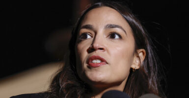 Alexandria Ocasio-Cortez speaks in front of a microphone