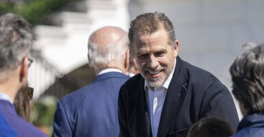 Hunter Biden in a black suit smiles as Joe Biden in a blue suit walks away