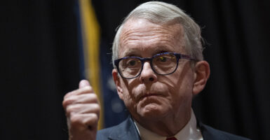 Ohio Gov. Mike DeWine makes a thumbs up gesture in a suit