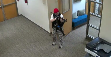 Audrey Hale in camouflage pants levels a gun at a printer in Nashville's Covenant School
