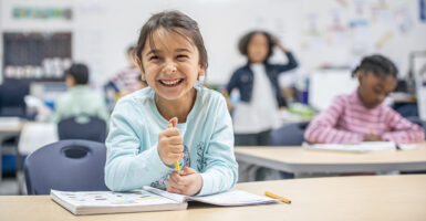 Young Girl in Class at Her Desk Laughing