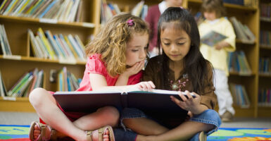 Two girls read book in children's library