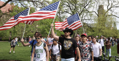 University of Chicago counter-protesters raise American flags into the air, wearing t-shirts.