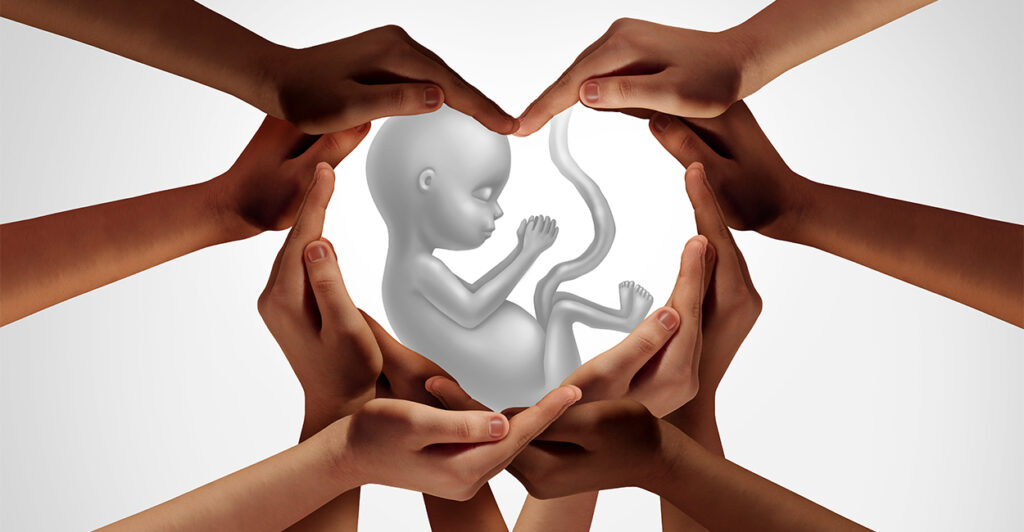 group of hands joined together forming a heart shape around a baby in the womb