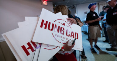 A woman holds campaign signs for Hung Cao.