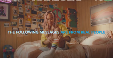 A girl puts on a rainbow-patterned sock while sitting on her bed.