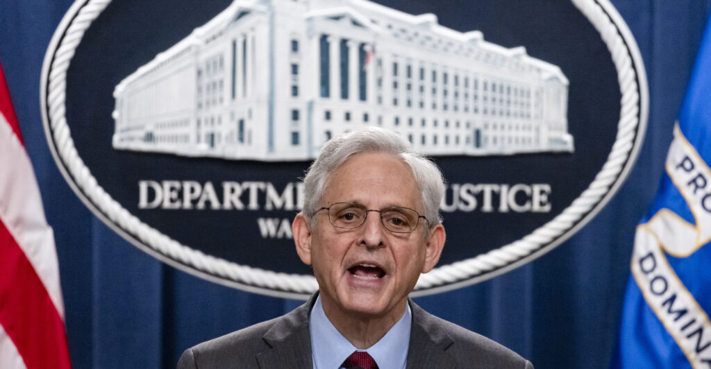 Merrick Garland speaks at a podium in front of the Department of Justice emblem.