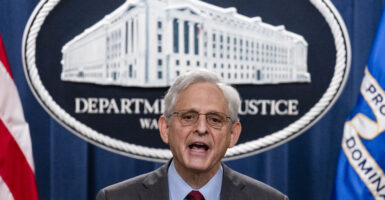 Merrick Garland speaks at a podium in front of the Department of Justice emblem.
