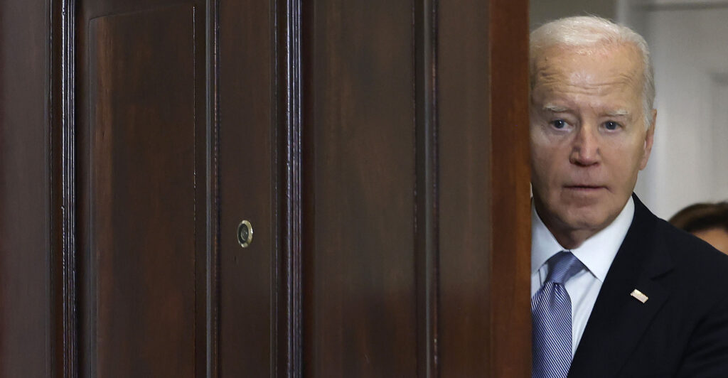 Joe Biden peeks out a door.