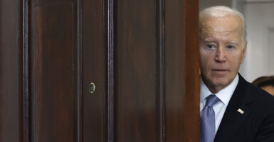 Joe Biden peeks out a door.