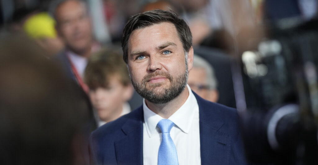 J.D. Vance looks upward, wearing a light blue tie and navy blue suit.