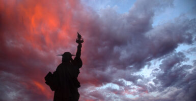 A silhouette of the Statue of Liberty with a sunset background.