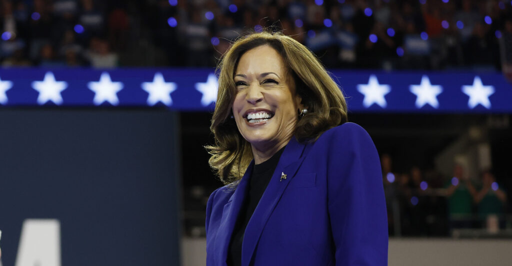 Kamala Harris in a dark blue suit speaks at a campaign rally.