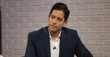 Michael Knowles in a black sport coat and a white shirt stares intently