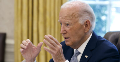 Joe Biden in a blue suit gestures in the White House