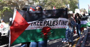 A woman marches with a sign reading "Free Palestine" with blood all over it