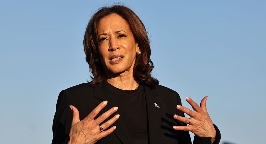 Kamala Harris gestures while wearing a black suit
