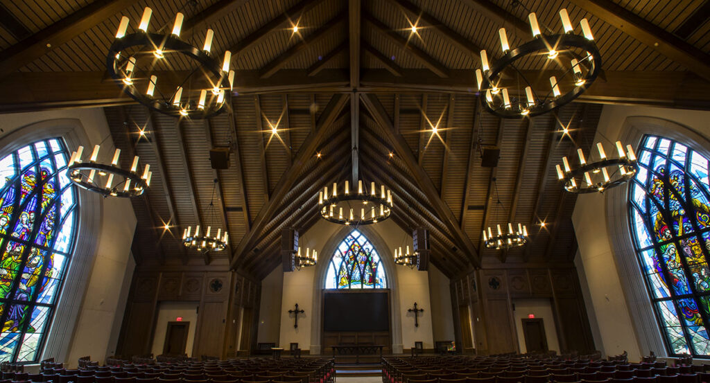 The interior of Parish Life Center in Houston, Texas, with stained glass windows and candles