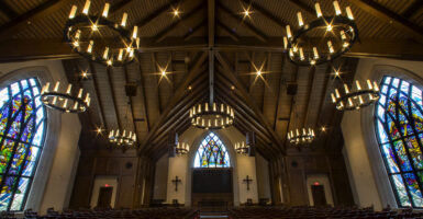 The interior of Parish Life Center in Houston, Texas, with stained glass windows and candles