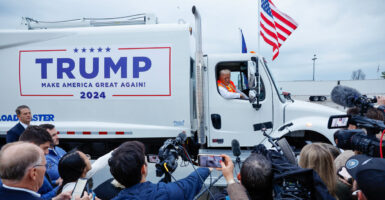 Donald Trump hosts a news conference while seated in a garbage truck with campaign signage on the side