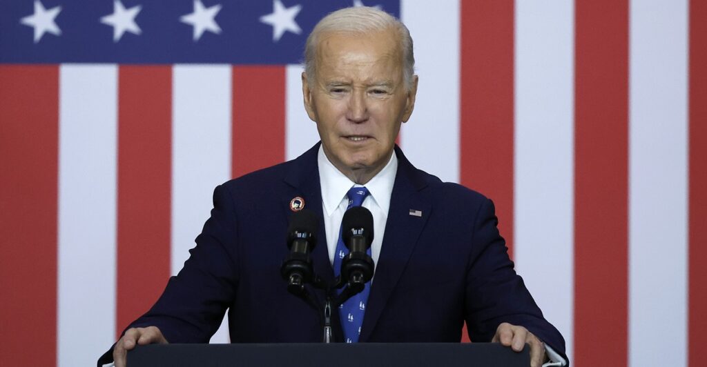 President Joe Biden stands at a podium with an American flag behind him.