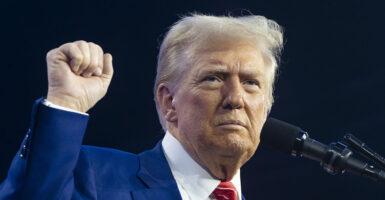 Donald Trump raises his fist in a blue suit