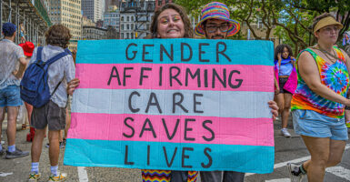 An activist holds a sign reading, "Gender-affirming care saves lives."