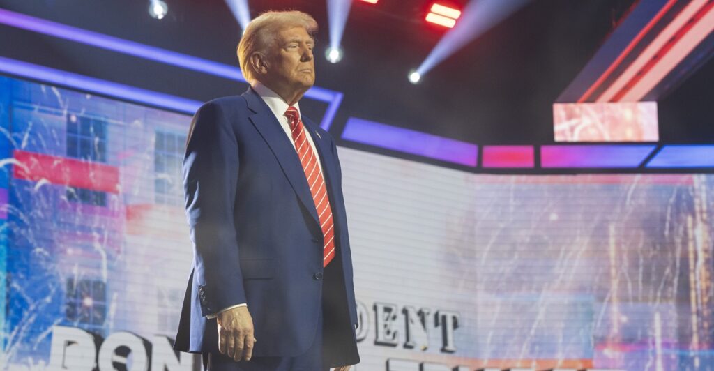 President-elect Donal Trump stands on a stage with his arms by his side looking forward.
