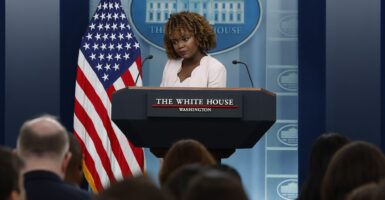 White House press secretary Karine Jean-Pierre speaks during a news conference, standing next to an American flag.