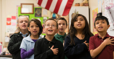 Elementary school-age children pledge allegiance to the American flag.