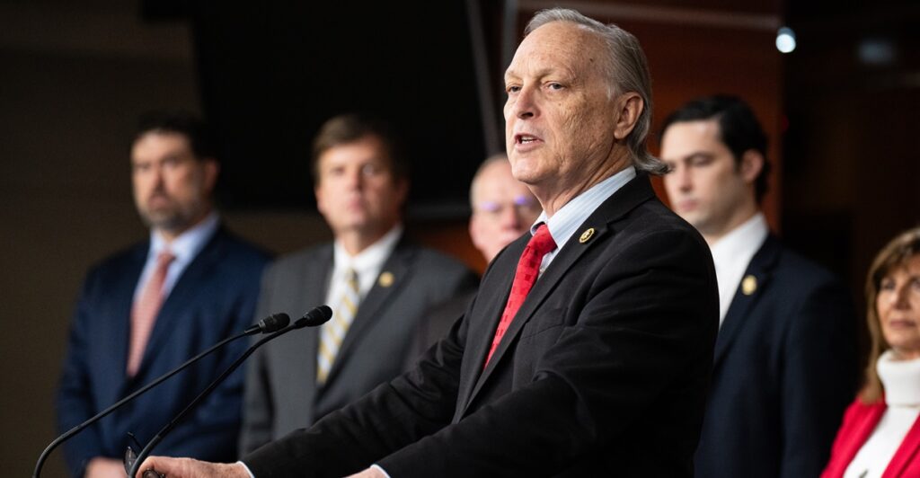 Andy Biggs looks to his right while speaking at a podium.