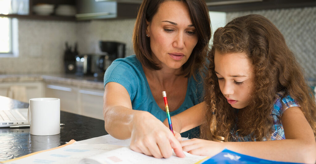 A mother helps her daughter with her homework in the family kitchen.
