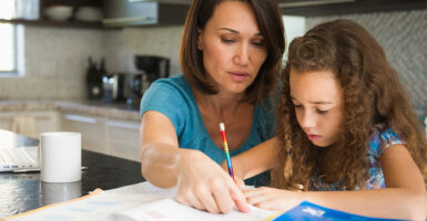 A mother helps her daughter with her homework in the family kitchen.