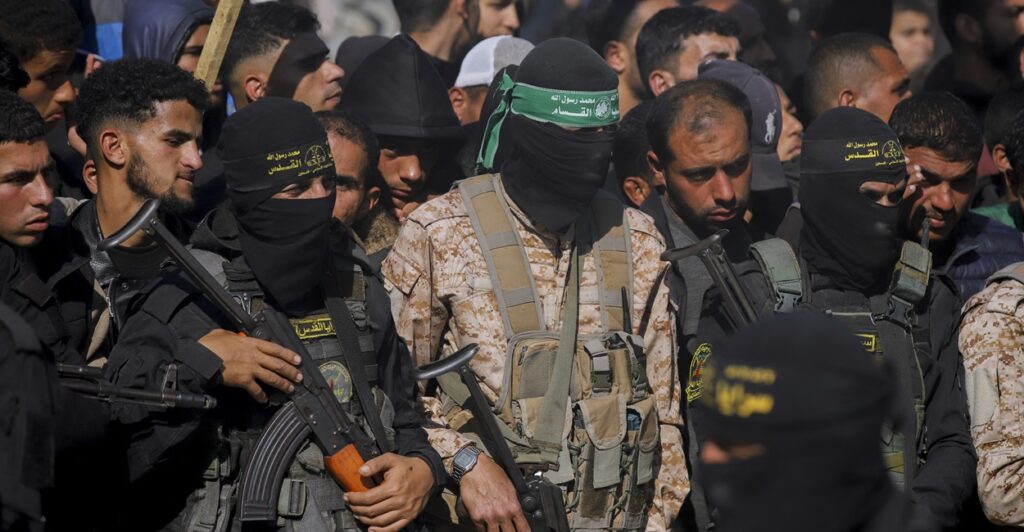Hamas militants stand while holding machine surrounded by a crowd of people.